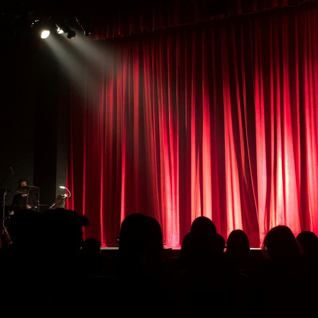 A-stage-with-a-red-curtain-background-ready-to-welcome-a-performer-stock-monica-713149__FocusFillMaxWyItMC40MCIsIjAuMDkiLDEwMjQsMTAyNF0_QualityWzg1XQ.jpg